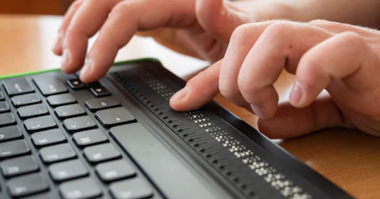 A close-up of hands using a braille keyboard for computer